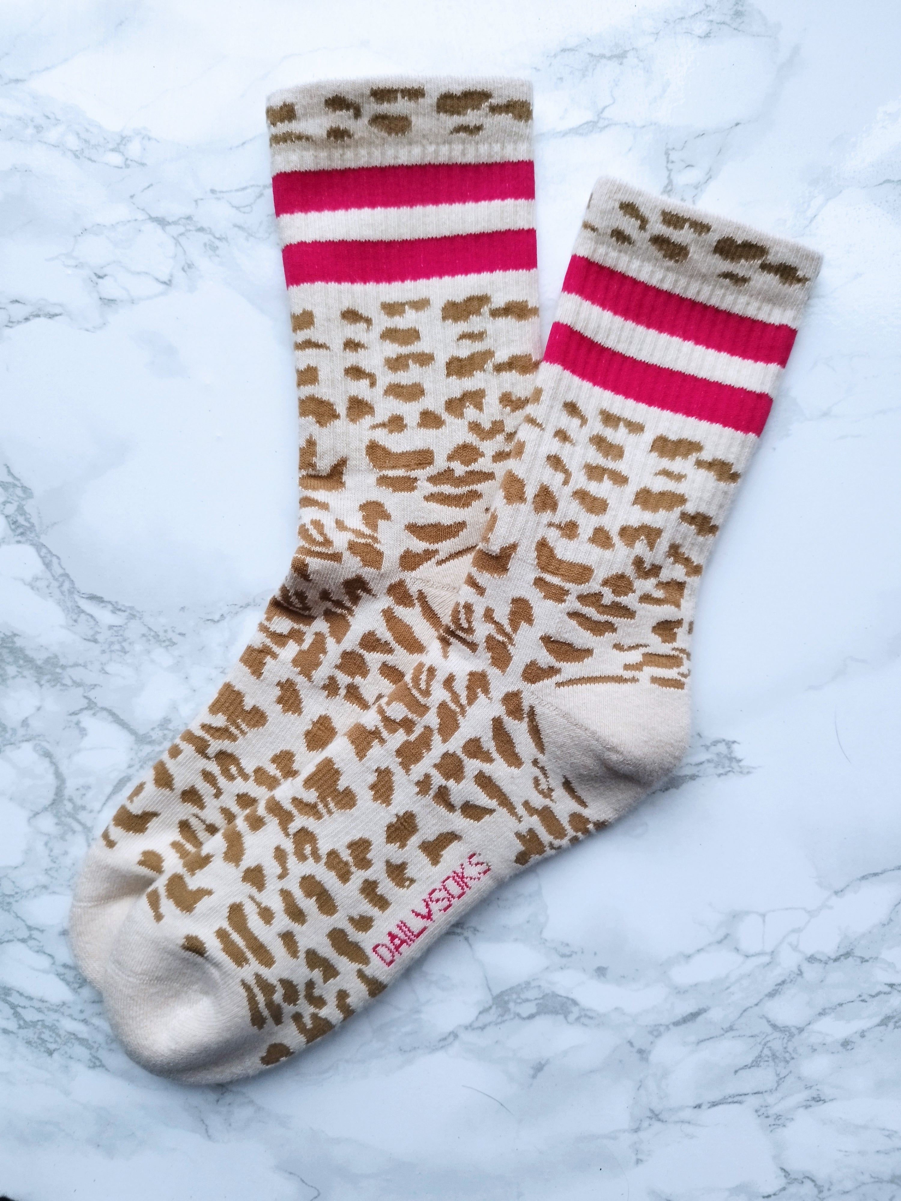 Produktbild von Tennissocken mit LEO Print und pinken Streifen auf dem Bett